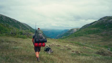 Un-Hombre-Y-Su-Perro-Caminan-Por-Las-Empinadas-Colinas-De-Osen,-En-El-Condado-De-Trøndelag,-Noruega.-Toma-Estática.