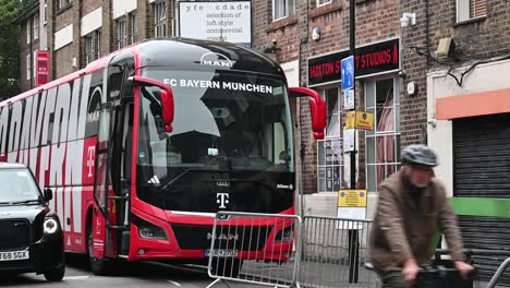 Cyclist-and-Taxi-coming-past-FC-Bayern-Munchen-Coach,-London,-United-Kingdo