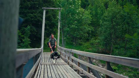 A-Man-and-His-Dog-are-Crossing-a-Small-Bridge-While-Hiking-Through-the-Forests-of-Osen,-Trøndelag-County,-Norway---Static-Shot