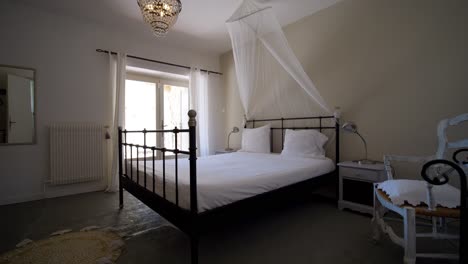 Elegant-minimalistic-bedroom-with-metal-bed,-white-canopy,-crystal-chandelier