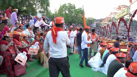 Gran-Concentración-De-Personas-En-Un-Evento-Público-De-La-Campaña-Electoral-Del-BJP-En-La-Lok-Sabha,-Distribución-De-Mercadería-De-Namo-Entre-La-Gente-Por-Parte-De-Trabajadores-Del-Partido-En-Assi-Ghat