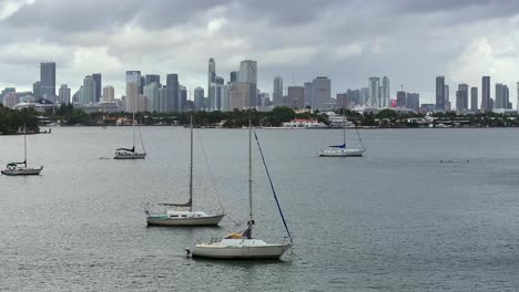 Barcos-De-Vela-Anclados-En-La-Bahía-Del-Río-Frente-Al-Horizonte-De-Miami-Con-Nubes-En-El-Cielo