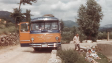 1960s-Bus-Stopped-Roadside-with-Passengers-Relaxing-by-River-During-Journey