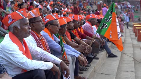 Group-of-Indian-people-sitting-in-row-wearing-BJP-merchandise-gathered-to-support-Chief-Minister-Yogi-Adityanath-Lok-Sabha-election-campaign-rally