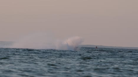 Man-riding-a-jet-ski,-water-spraying-in-golden-sunset-light