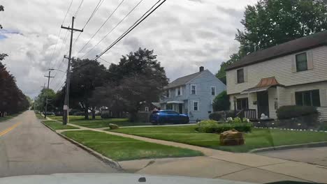 Dashcam-footage-of-a-car-driving-through-a-suburban-neighborhood-with-lush-trees-and-houses