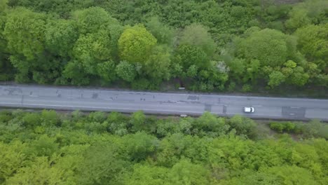 Drone-footage-of-a-car-riding-on-a-long-road-from-above