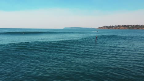 Hydro-foiling-along-ocean-waves-in-Sydney,-pull-up-to-reveal-foiler-on-wave-behind-aerial