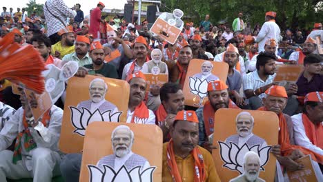 Bharatiya-Janata-Party-election-campaign,-Party-supporters-with-Namo-merchandise,-India-Prime-Minister-Narendra-Modi's-face-poster-with-BJP-party-symbol