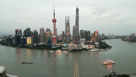 Shanghai-iconic-famous-business-district,-aerial-drone-panoramic-cityscape-of-China-after-the-river,-sailboat-at-illuminated-night