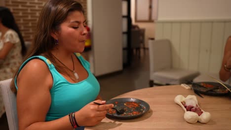 Woman-in-a-turquoise-top-enjoys-a-meal-served-in-a-bone-shaped-dish-in-a-restaurant