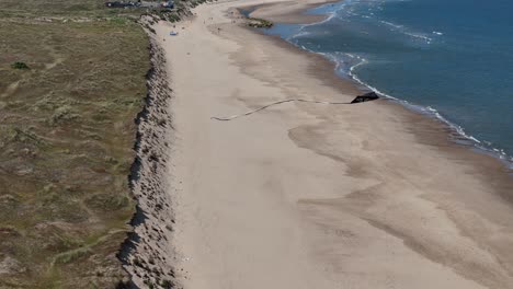 Vista-Aérea-De-Un-Dron-Con-Vista-Aérea-De-Una-Cometa-Volando-Sobre-La-Costa-Norte-De-Norfolk,-Reino-Unido