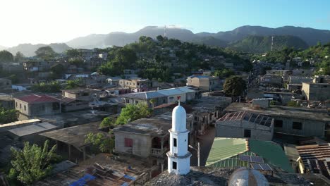 Aerial-close-up-of-white-stone-old-Muslim-mosque-in-Mohéli-or-Mwali,-part-of-the-Union-of-the-Comoros,-drone-fly-above-small-beach-town-during-warm-afternoon-light