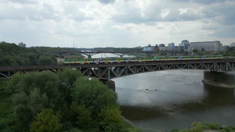 Towards-stadium-structure,-train-travels-on-bridge-over-Vistula-river