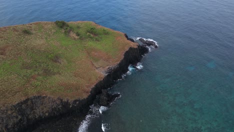 aerial-view-of-Mohéli-or-Mwali,-part-of-the-Union-of-the-Comoros,-the-smallest-of-the-three-major-volcanic-islands-in-the-country,-drone-approaching-the-waves-crashing-on-the-rock