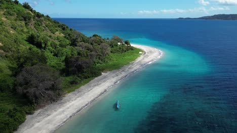 aerial-of-lonely-boat-on-remote-tropical-islet-white-sand-beach-in-Mohéli-or-Mwali,-part-of-the-Union-of-the-Comoros,-Africa’s-east-coast,-blue-Indian-Ocean-waters