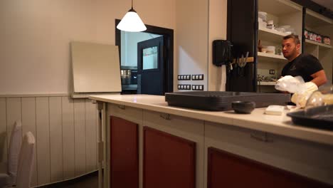 Waiter-working-in-a-cozy-restaurant-kitchen,-holding-a-plate-of-food,-preparing-to-serve