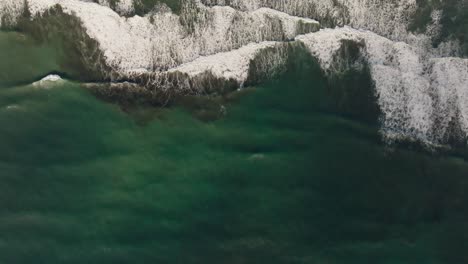 Turquoise-Atlantic-ocean-water-waves-crashing-on-empty-brown-beach-in-Iceland