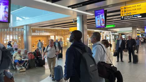 Busy-scene-of-passengers-in-traveling-at-Heathrow-Airport-checking-gate-information-on-electronic-boards