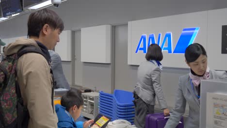 Eine-Konzentrierte-Szene-Am-Flughafen-Kansai-In-Osaka,-Wo-Ein-Passagier-Den-Check-in-Prozess-Mit-Dem-ANA-Personal-Am-Schalter-Abschließt