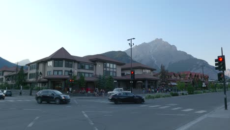 Vista-Panorámica-De-La-Calle-De-Coches-Conduciendo-Por-La-Ciudad-De-Banff-Con-Fondo-De-Montaña