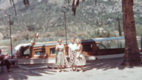 Tres-Mujeres-Charlando-Después-De-Un-Paseo-En-Barco-Bajo-Las-Palmeras,-Dubrovnik,-Década-De-1960