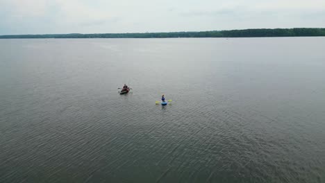 Drone-view-of-two-kayakers-paddling-across-a-vast-lake,-showcasing-adventure-and-tranquility