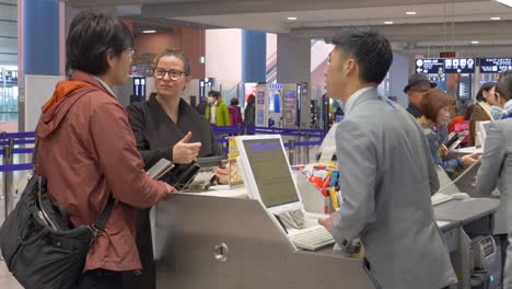 Fängt-Einen-Spontanen-Moment-Am-Flughafen-Kansai-In-Osaka-Ein,-Wo-Sich-Ein-Passagier-Und-Ein-ANA-Mitarbeiter-Am-Schalter-Der-Fluggesellschaft-Unterhalten