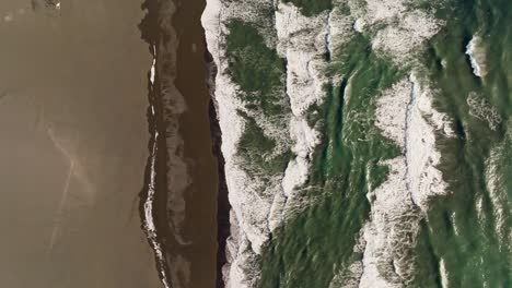 Aerial-top-down-view-waves-crashing-at-beach-in-Iceland-on-a-sunny-day