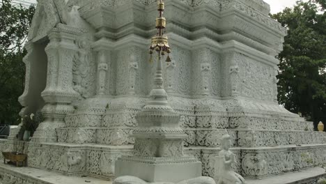 Ornate-White-Stupa-at-Wat-Pan-Whaen,-tilt-down-to-beautiful-elephant-sculpture,-fine-details-and-stunning-carved-clean-lines-in-Chiang-Mai-Thailand