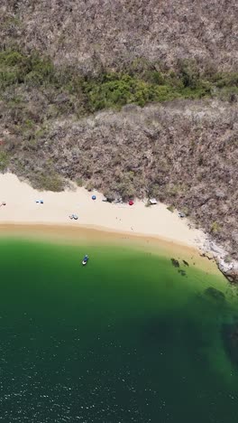 Vertical-drone-shot-of-a-beach-in-Huatulco,-Oaxaca,-as-it-ascends