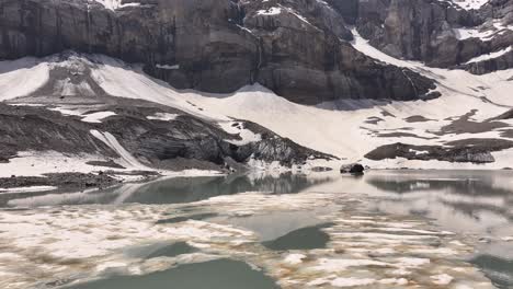 Serene-alpine-lake-reflecting-snowy-cliffs-and-mountains-at-Klausenpass-in-the-Swiss-Alps,-Switzerland