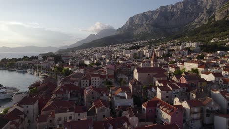 Makarska,-croatia-with-red-roofed-buildings-and-marina-at-sunset,-aerial-view