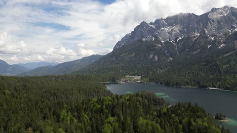 Vista-Aérea-Sobre-El-Lago-Eibsee,-En-Alemania,-Grainau,-Rodeado-De-Impresionantes-Montañas,-Paz-Y-Belleza-En-La-Naturaleza,-Con-Montañas-Cubiertas-De-Nieve,-Un-Hermoso-Cielo,-Ricos-Bosques-Alpinos-Y-Pequeñas-Islas.