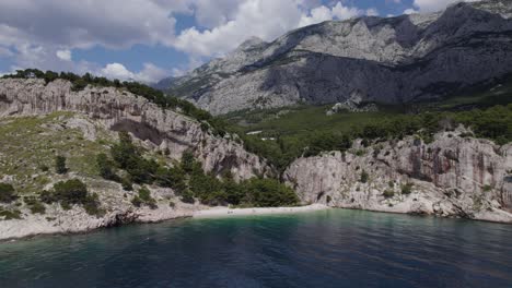 Aerial-backwards-ascend-from-isolated-Nugal-beach-near-cliff,-Croatia