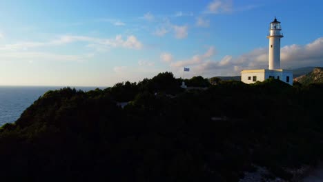 Old-lighthouse-on-the-cliff-of-Lefkada-Island-in-the-evening,-National-flag-of-Greece