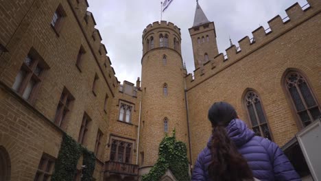 Mujer-Admirando-La-Intrincada-Arquitectura-Del-Castillo-De-Hohenzollern-En-Alemania,-Enmarcado-Por-Muros-De-Piedra-Históricos