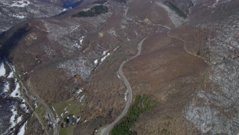 Upward-tilt-drone-shot-of-mountains-and-a-winding-road-below-in-Romania