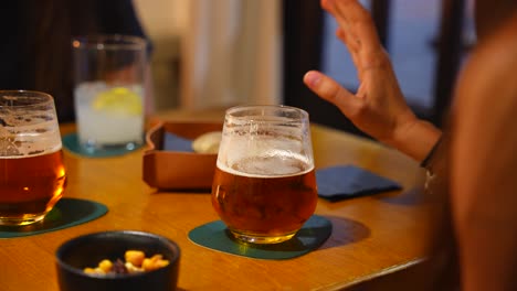 Close-up-of-hand-putting-a-drink-on-a-restaurant-table-during-a-lively-conversation