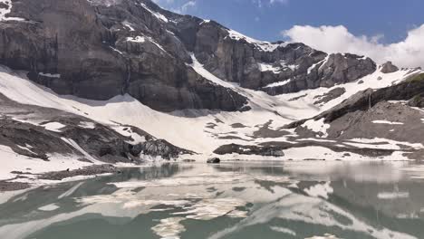 Snowy-mountains-reflecting-in-a-serene-lake-at-Klausenpass-in-the-Swiss-Alps,-Switzerland