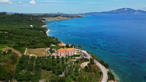 Panoramic-drone-reveals-Agios-Sostis-beach-landscape-in-Greece,-green-holiday-hills-destination,-skyline-background