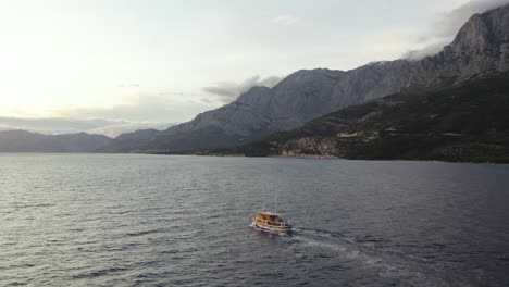 Barco-Navegando-Por-El-Mar-Adriático-En-La-Costa-De-Makarska-En-Croacia-Al-Atardecer,-Toma-Aérea