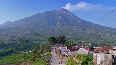 Aerial-view-of-beautiful-village-with-view-of-active-Merapi-Volcano-that-emits-smoke