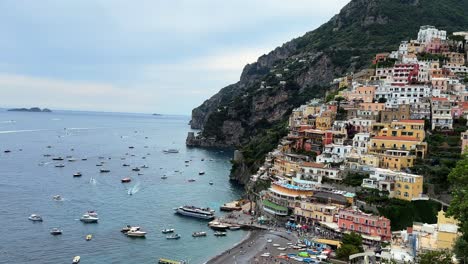 Picturesque-Italian-town-along-Amalfi-Coast,-colorful-Positano-mountainside,-pan-reveals-boats-in-ocean