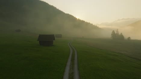 Early-morning-misty-sunrise-over-country-road-making-mysterious-mood-in-Wagenbrüchsee,-Germany,-aerial-view