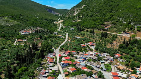 Hermoso-Pueblo-En-La-Colina-Con-Casas-Con-Techos-De-Tejas-Rojas-Y-Fondo-De-Montañas-Con-Colinas-Griegas