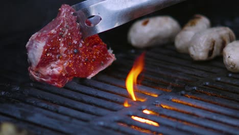 Der-Koch-Legt-Rohes,-Gewürztes-Rinderfiletsteak-Mit-Tropfendem-Olivenöl-Auf-Einen-Heißen-Grill-Und-Erzeugt-Flammen-In-Zeitlupe-4k