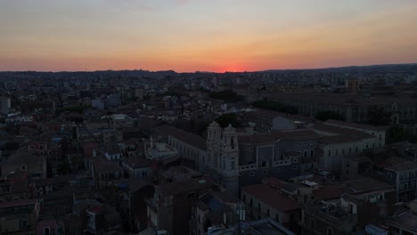 Catania-cityscape-at-dusk-with-a-vivid-sunset-sky,-aerial-view