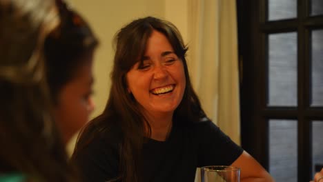 Woman-smiling-and-laughing-with-friends-while-conversing-at-a-restaurant