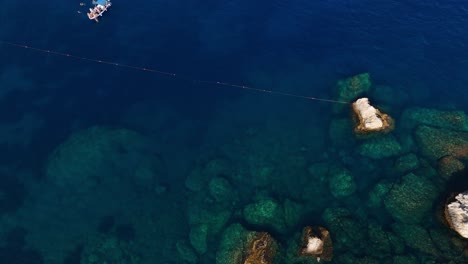 Clear-blue-water-and-rocks-along-the-coastline,-aerial-view